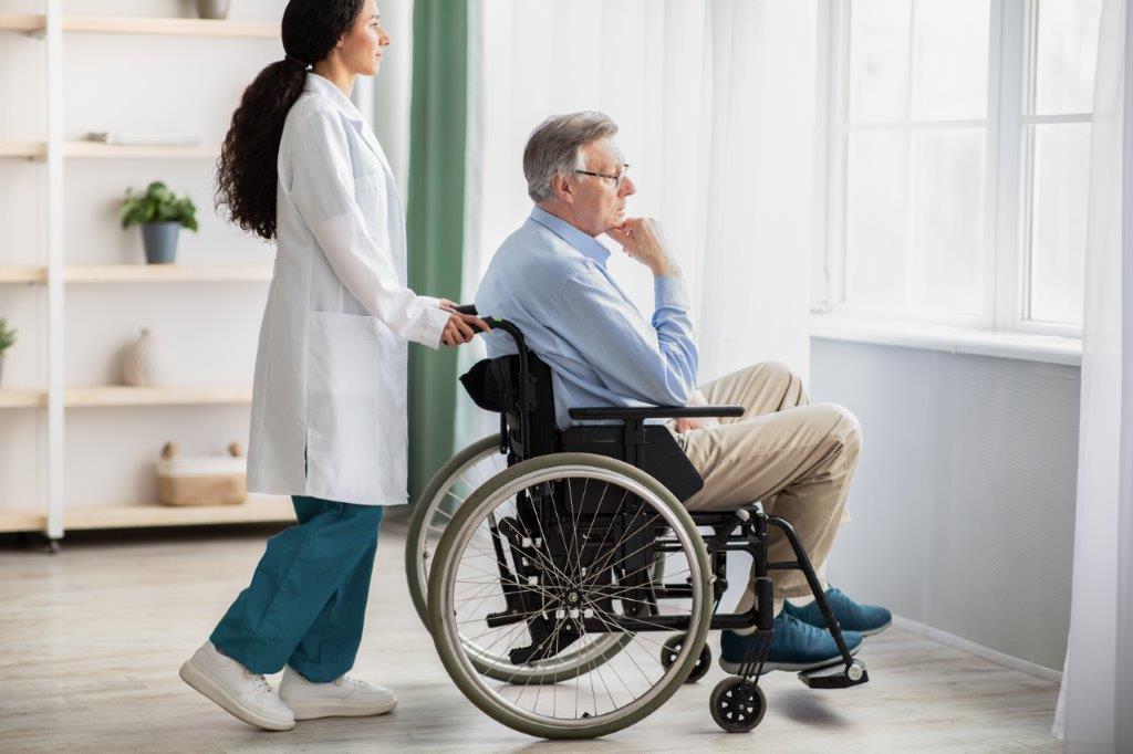 A healthcare professional assisting an older wheelchair user