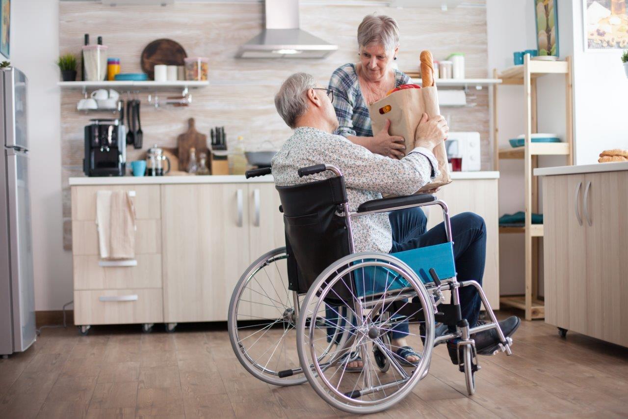 A woman supporting a man using a wheelchair at home